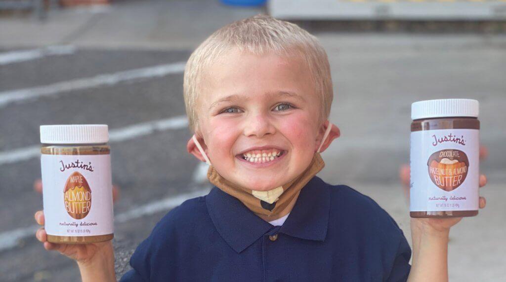 young boy smiling and holding Justin's jars in each hand