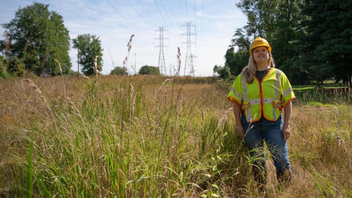 person standing in field with utility wires