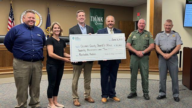 Six people posed, some holding a large check.