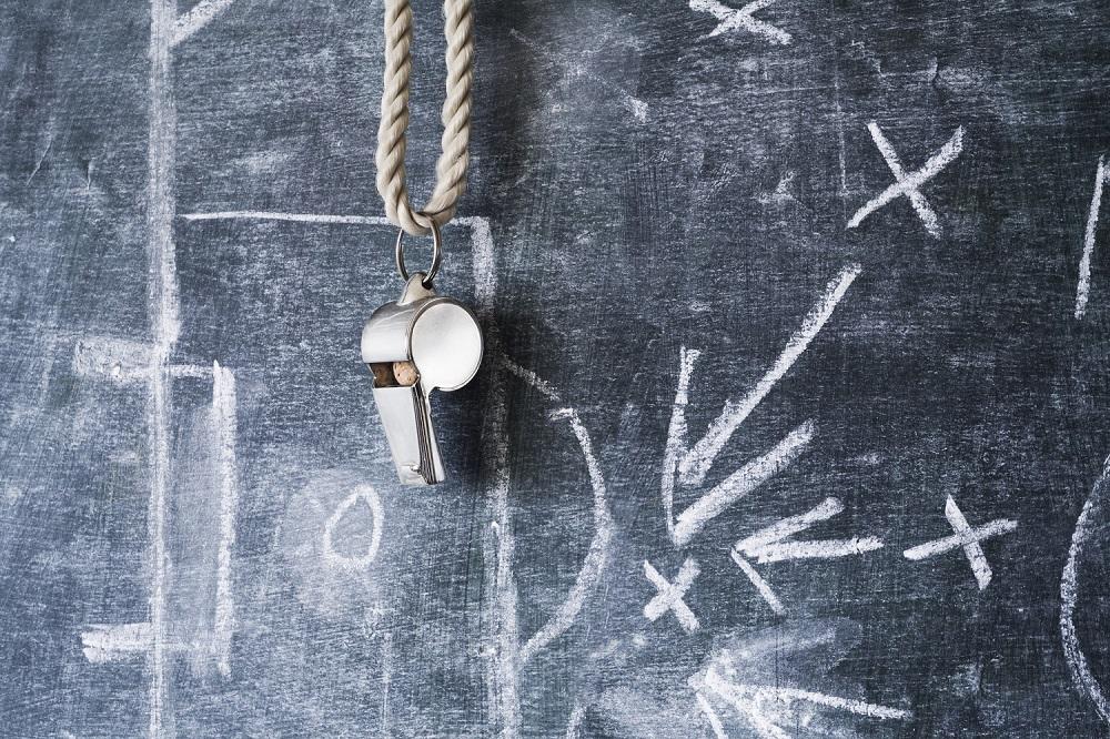 A coaches whistle hanging on a chalk board