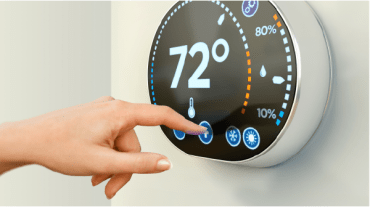 Hand setting temperature on thermostat.