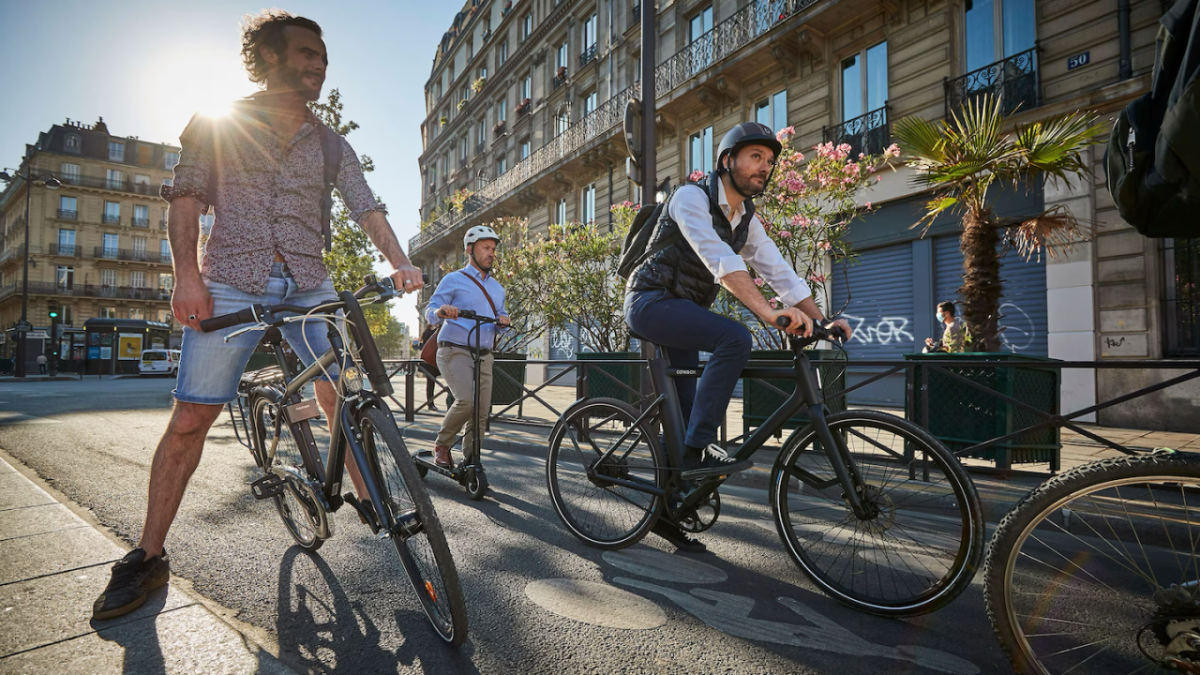 Two people on bikes and another on a scooter riding on the road