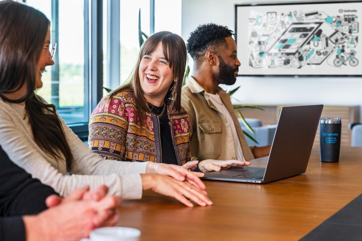 Three GoDaddy team members working together on a laptop.