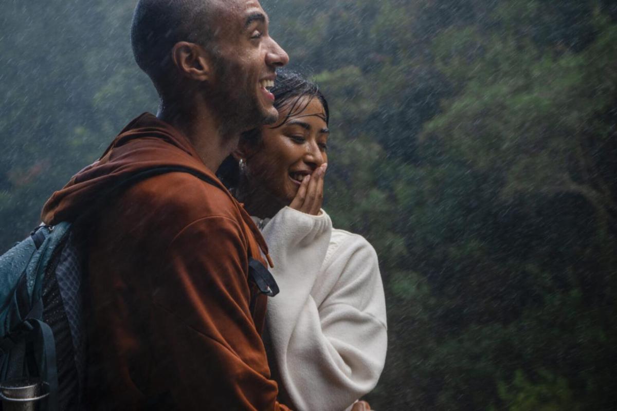 Two people stood close together, laughing in the rain