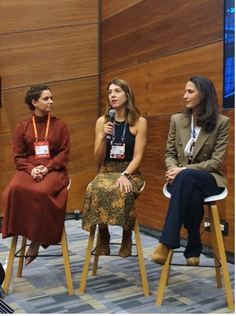 Three women seated on stools talking