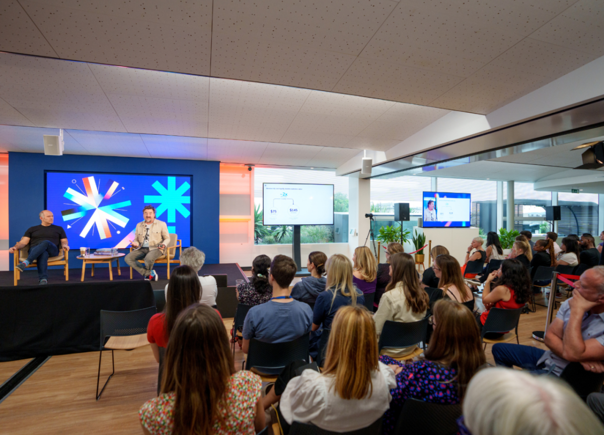 An audience listening to a talk by two people sat on stage