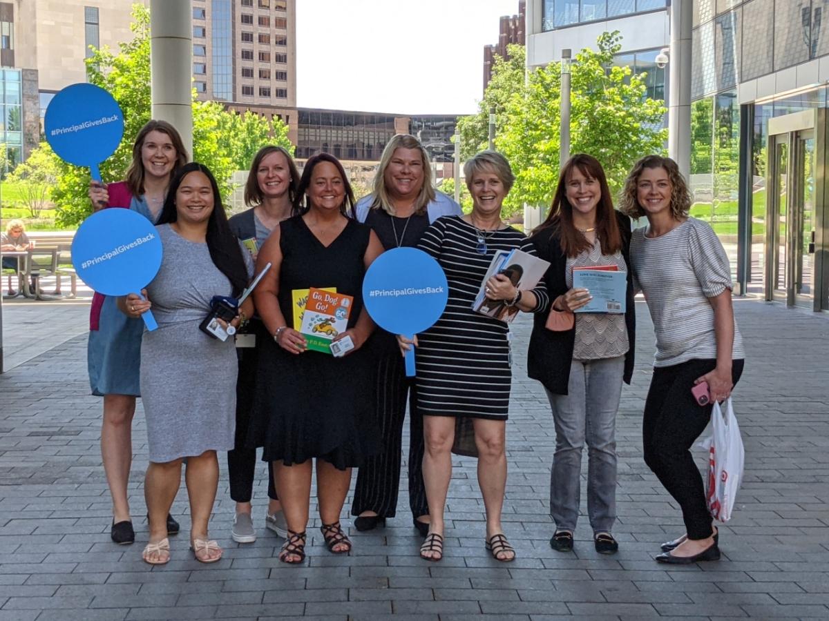 Principal Financial Group employees holding up signs that say Principal Gives Back.