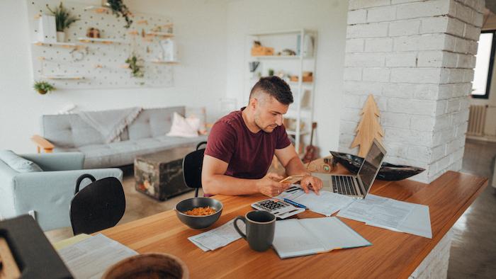 Man sitting at a desk at home in front of a laptop.