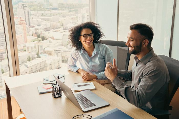 Two people at a conference room table having a discussion.