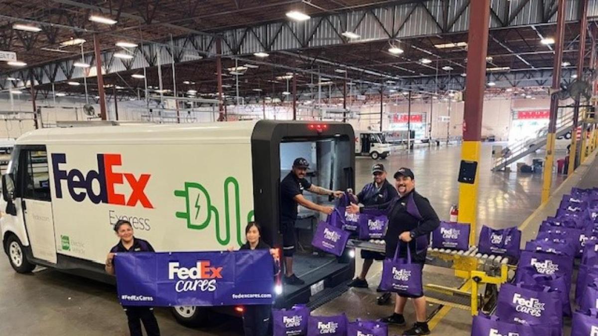 People taking FedEx totes out of a truck