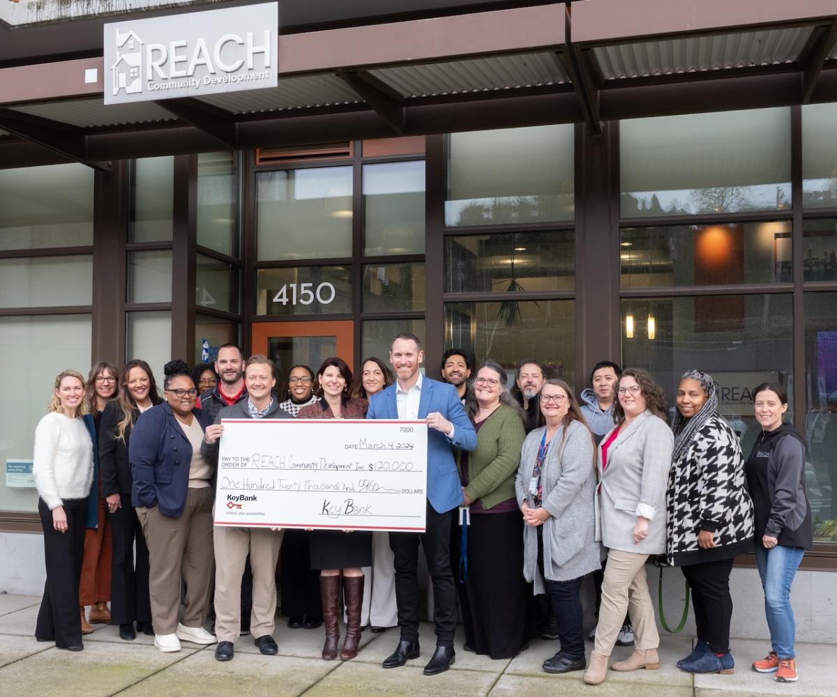 Representatives from KeyBank and REACH shown with a $120,000 grant check.