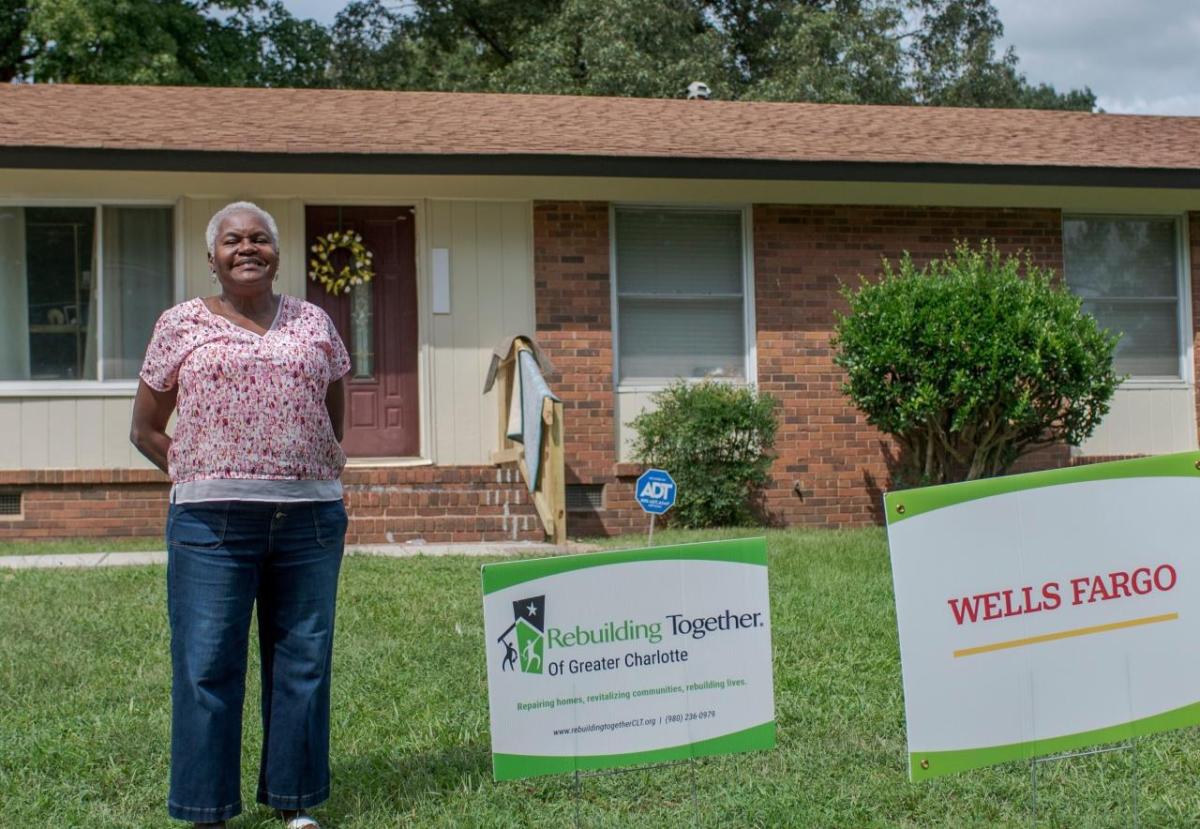 Woman stands in front of her house.