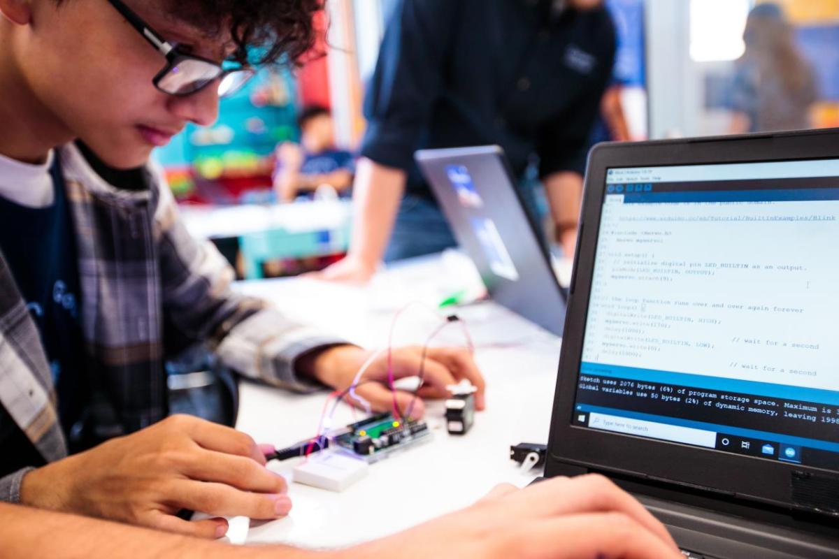 students work on a small circuit board and a laptop