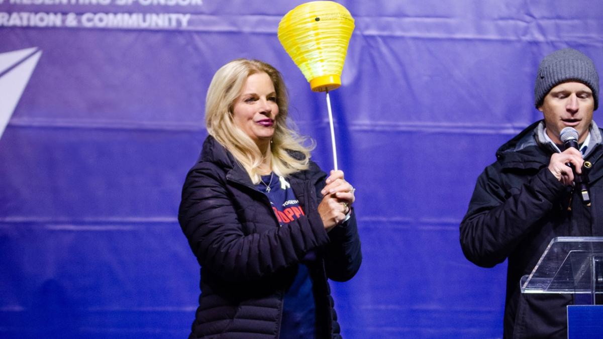 Rachel Howard holding a gold lantern. A person at a podium with a microphone beside her.