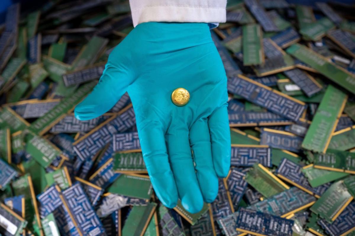 A person wearing gloves with a piece of recovered e-waste gold in the palm of their hand 