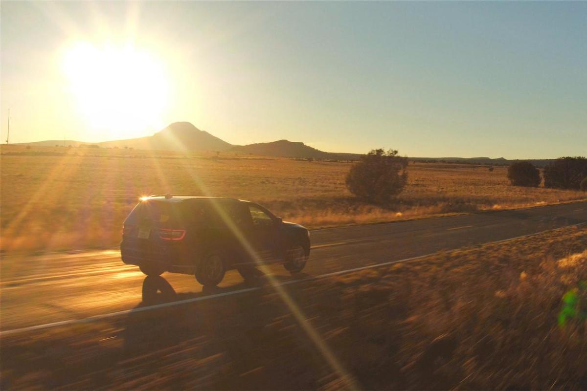 car driving along a road with the sun setting