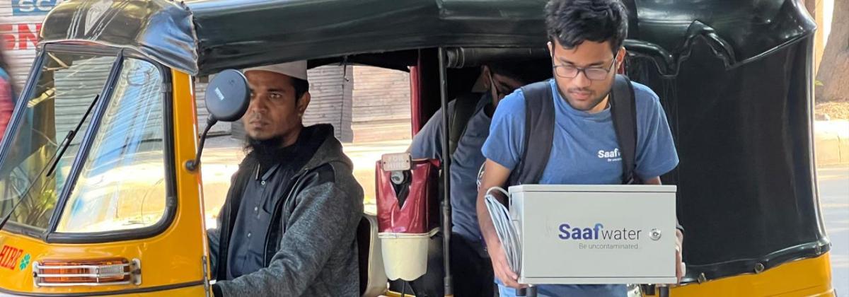 A person stepping out of a taxi carrying a Saafwater box.