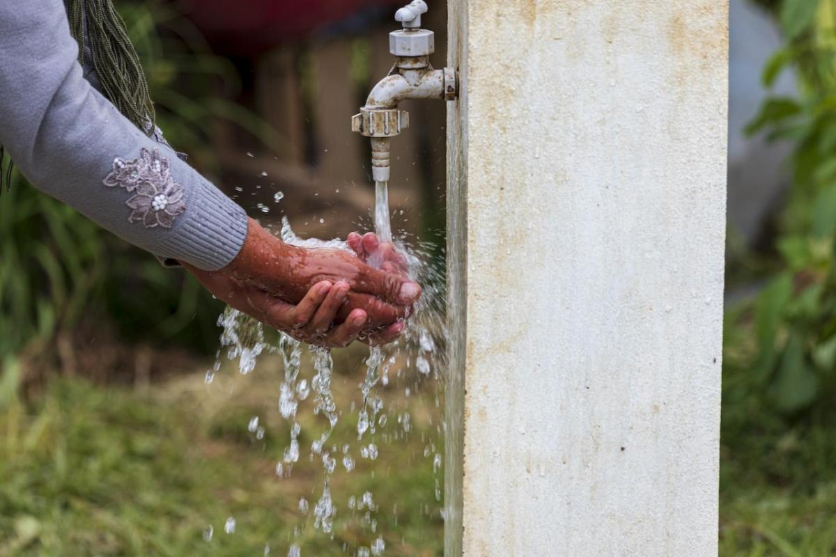 Hands being washed under outdoor faucet