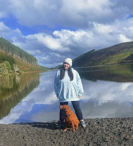 Sarah shown with her dog in front of a mountain lake.