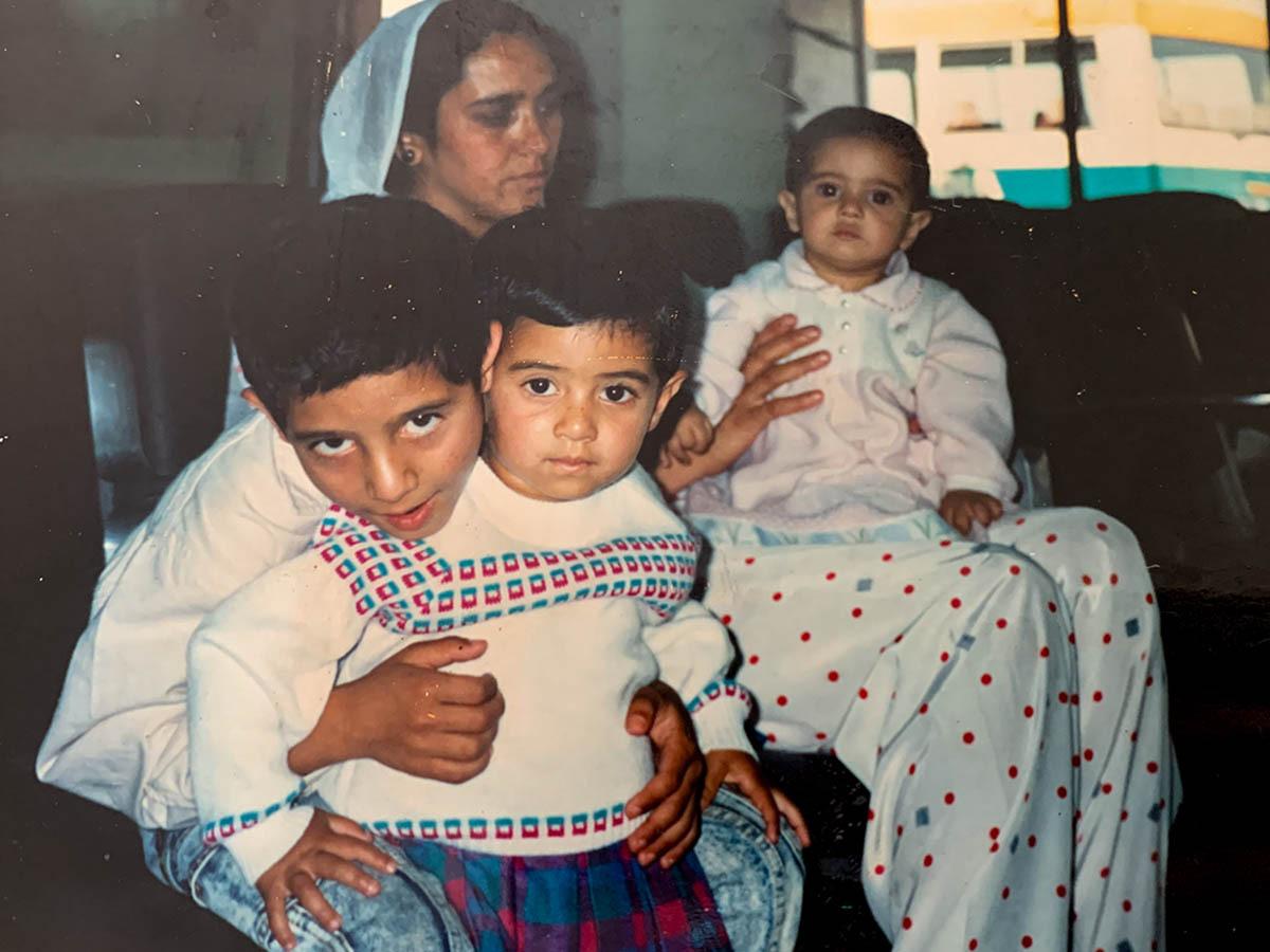 A family photo of a young child on a persons lap and two children sat together