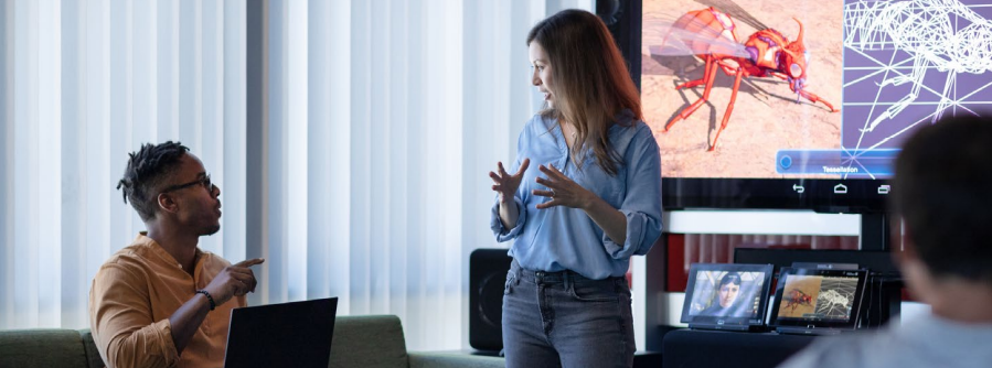 Employees talking in front of large monitor