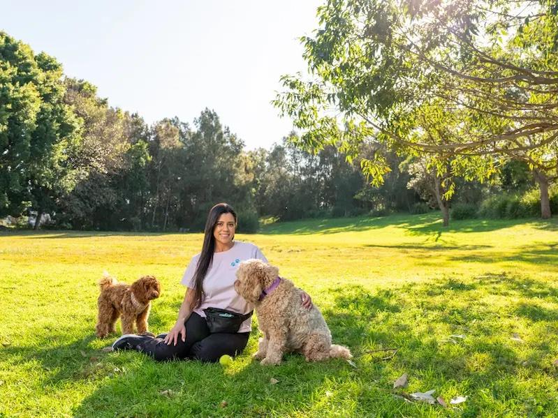 Young woman seated on the grass with her two dogs.