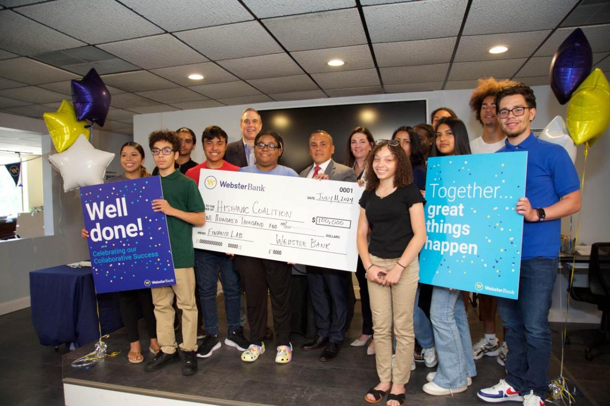 Group holding an oversized check and celebratory signs