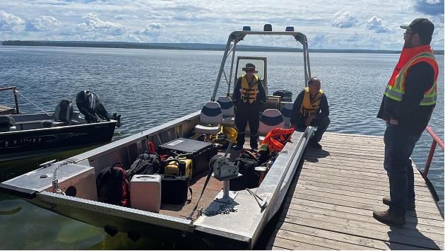 A search and rescue boat next to a pier, people in high-vis jackets on the boat and pier.