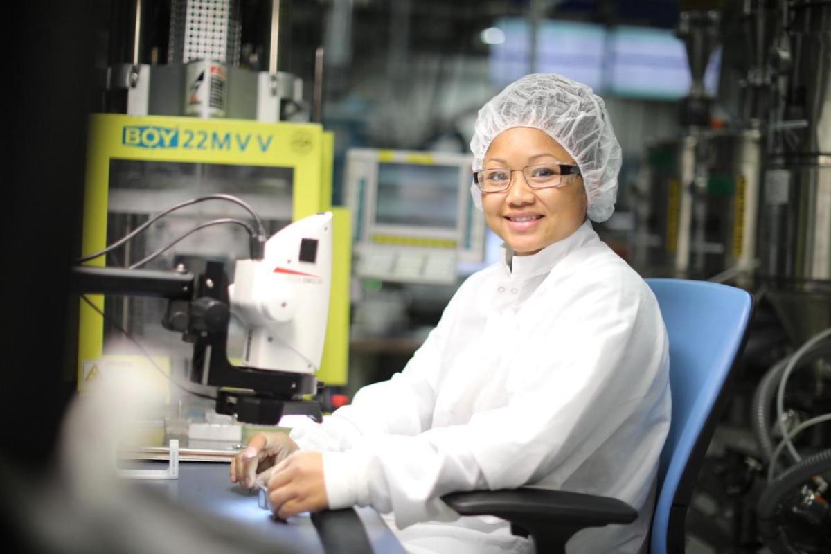 Person in white lab coat using microscope