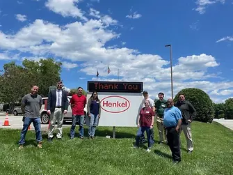 9 people in front of thank you Henkel sign