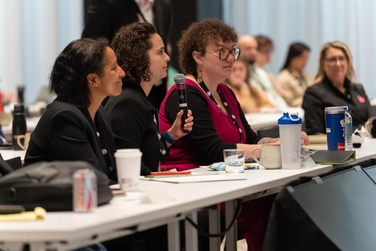 Three attendees engage in discussion at Sustainability LIVE Chicago 2025, with one woman holding a microphone.