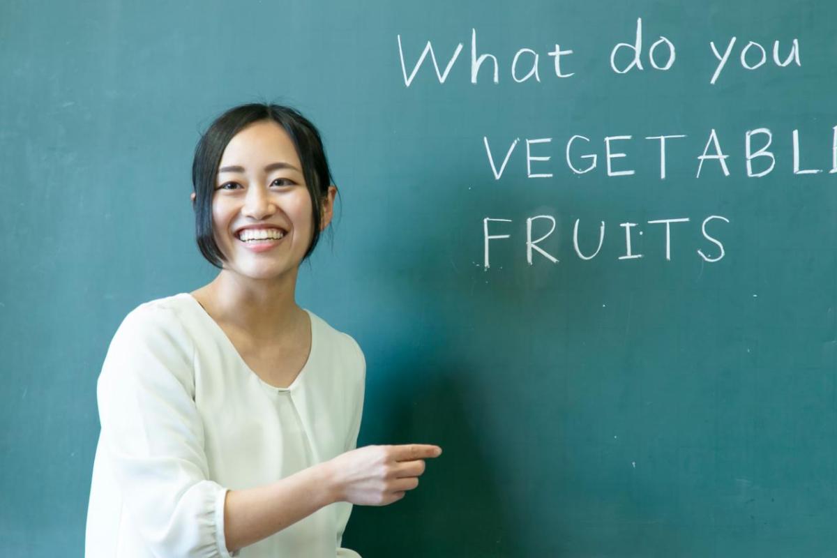 An adult stood next to a chalk board 