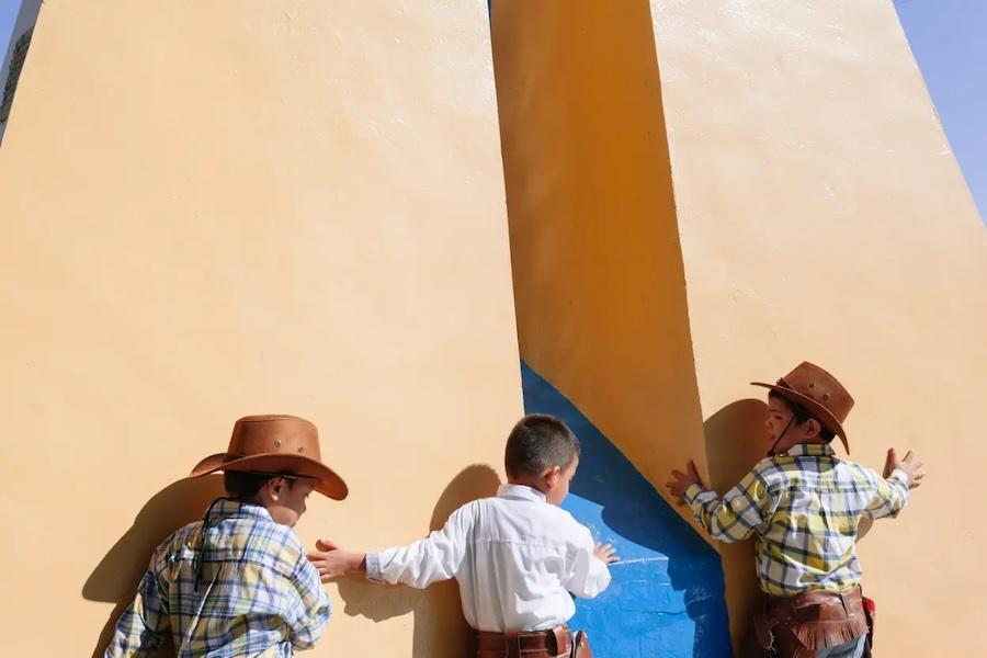 Thomas Allison photograph of three children playing; dressed as cowboys.