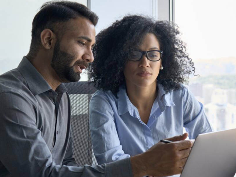 Two people sat next to each other looking at a laptop screen