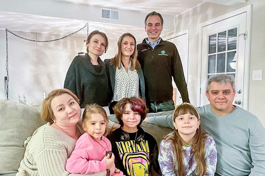 Regions associates stand behind the family sitting on a couch.