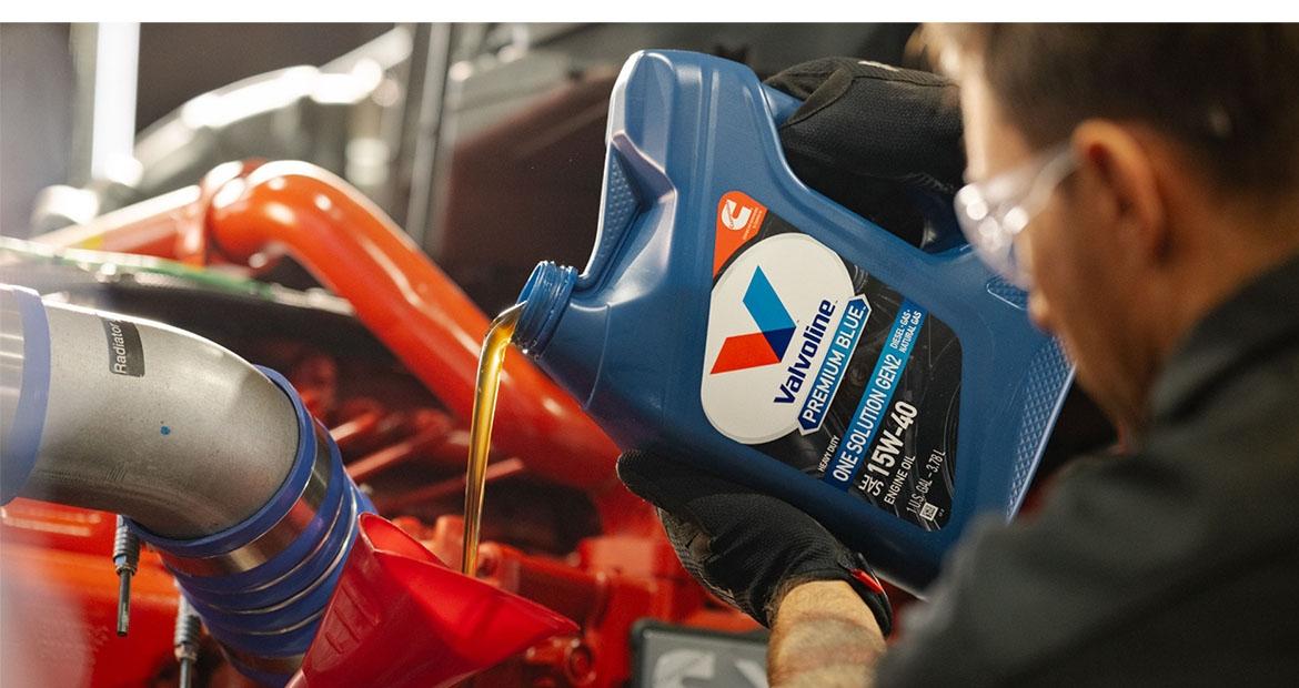 A person pouring a bottle of motor oil 