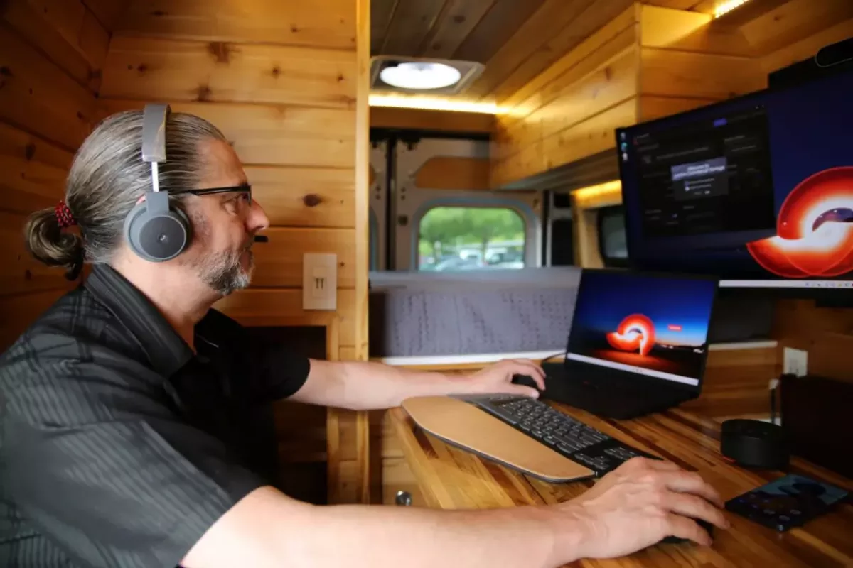 A person inside the van working on a tablet with other computer screens.