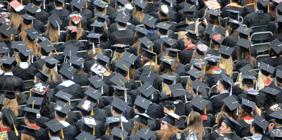 Students shown in cap and gowns at a graduation ceremony.