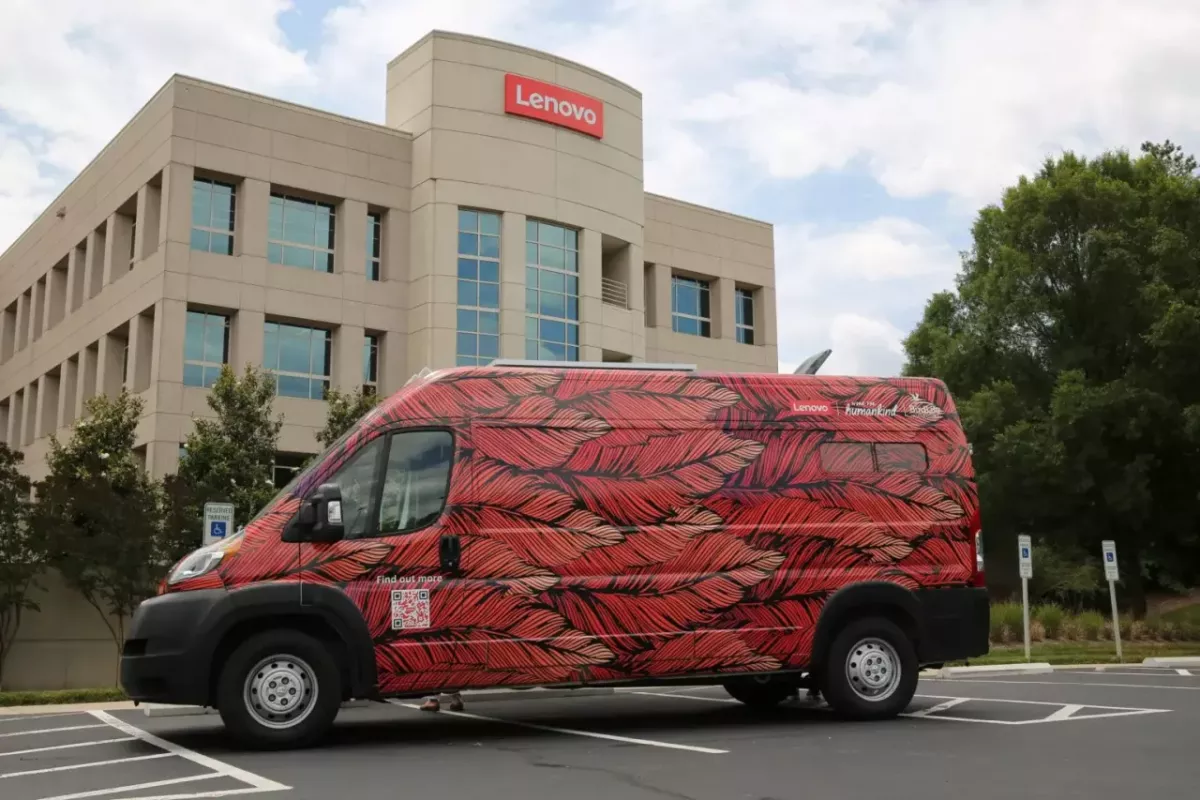 A colorful feather patterned van in a lot outside a Lenovo building.