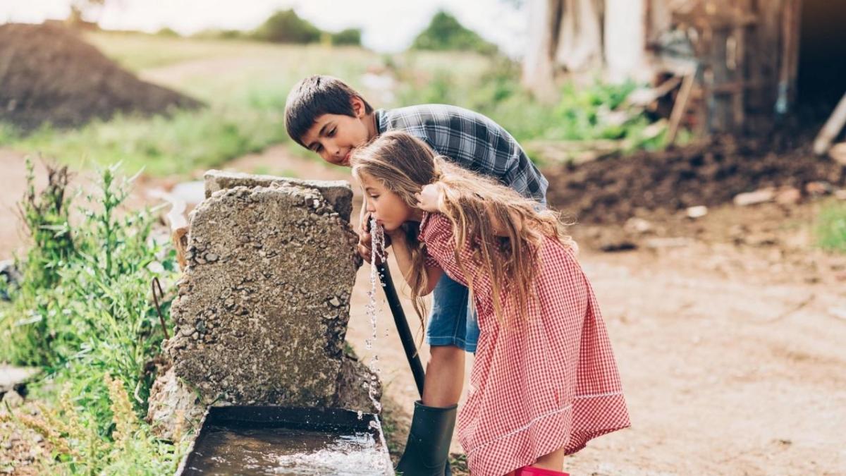 Girl and boy drinking from a fountain
