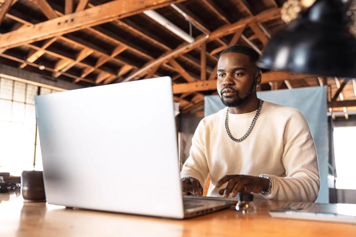 Male sitting in front of a laptop at a desk.