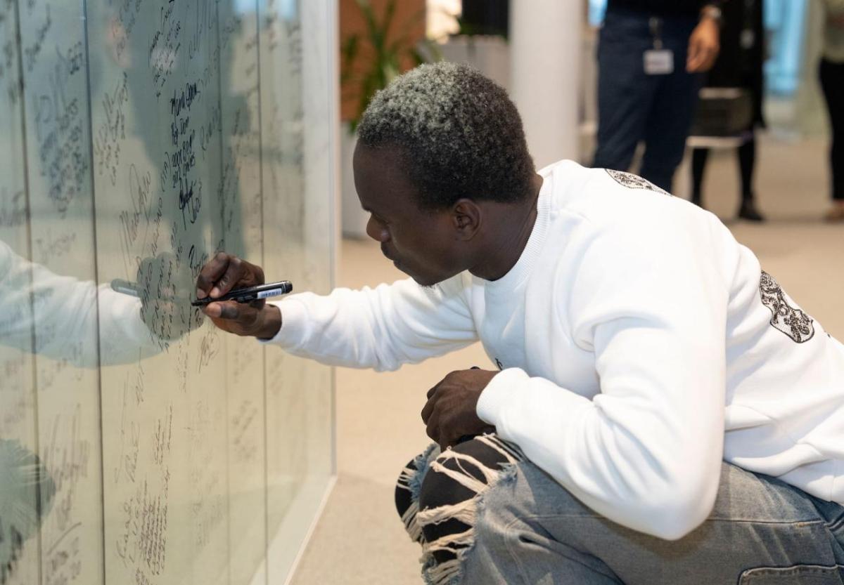 A person knelt down writing on a white board