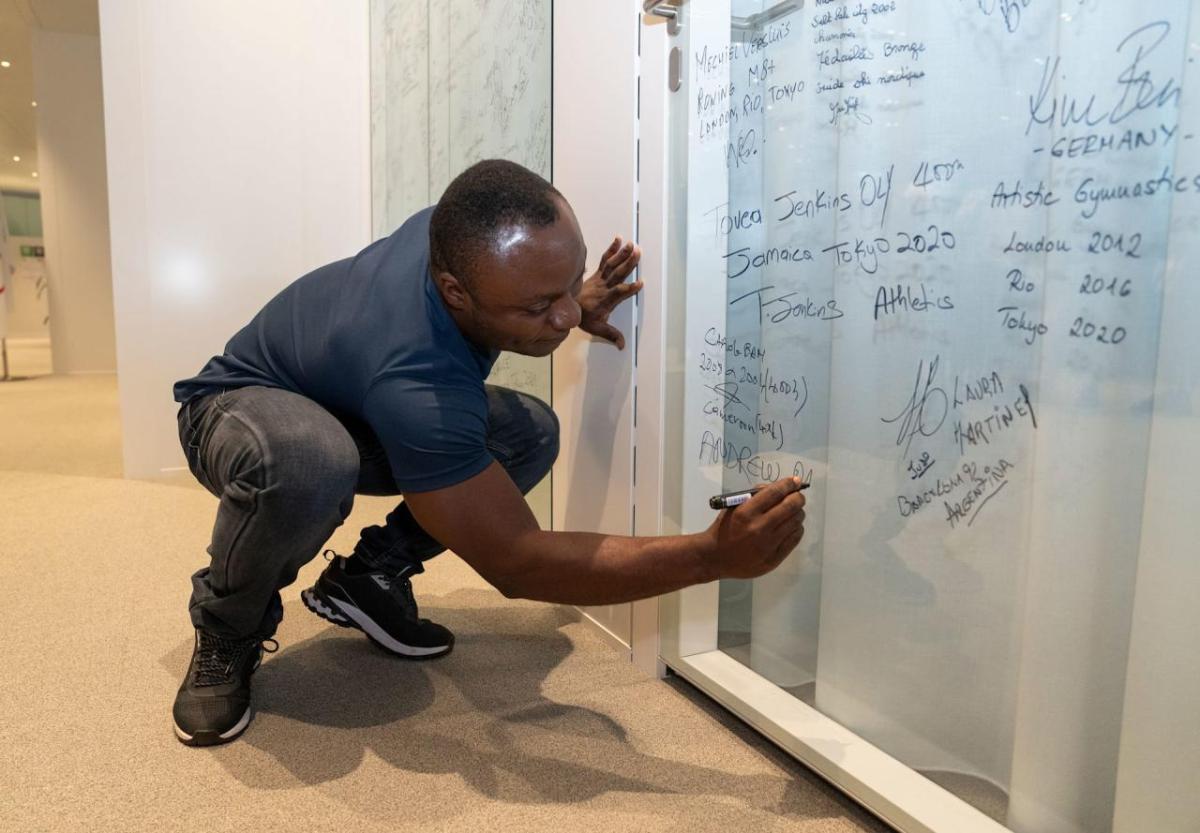 A person knelt down writing on a white board