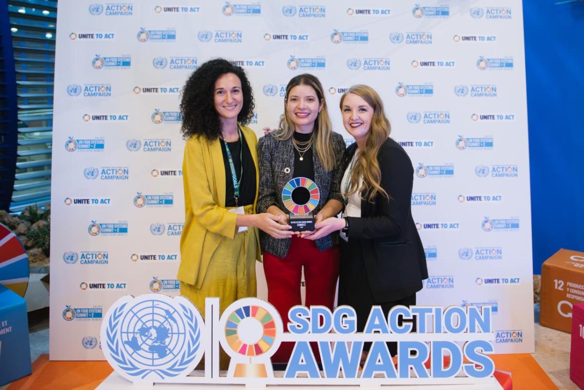 Three smiling people holding an award.