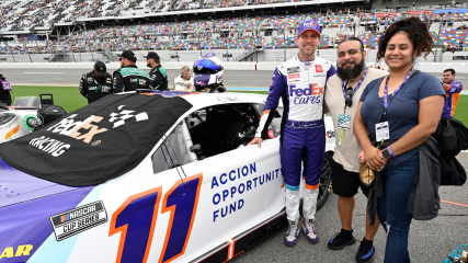 Three people standing next to a race car, number 11,  on a track.