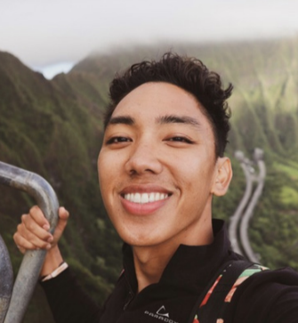 a person holding a rail and a large mountain behind them