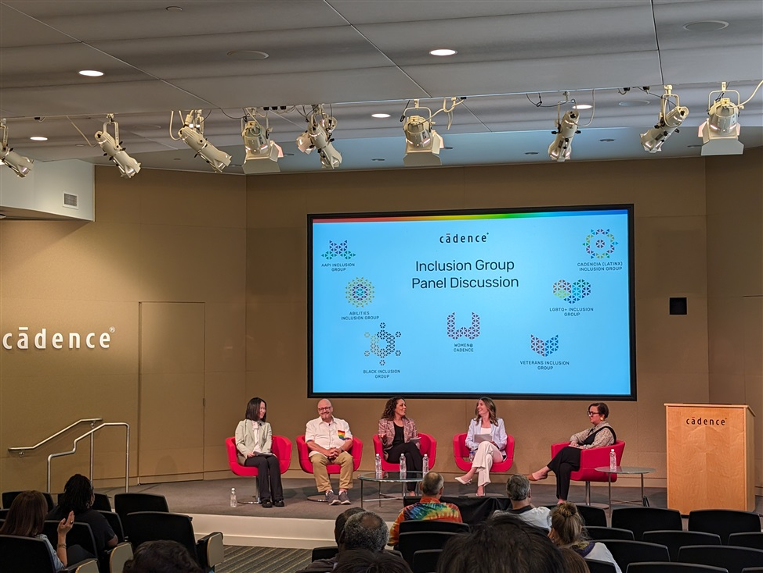 five people on a stage in red chairs with a projection screen behind them