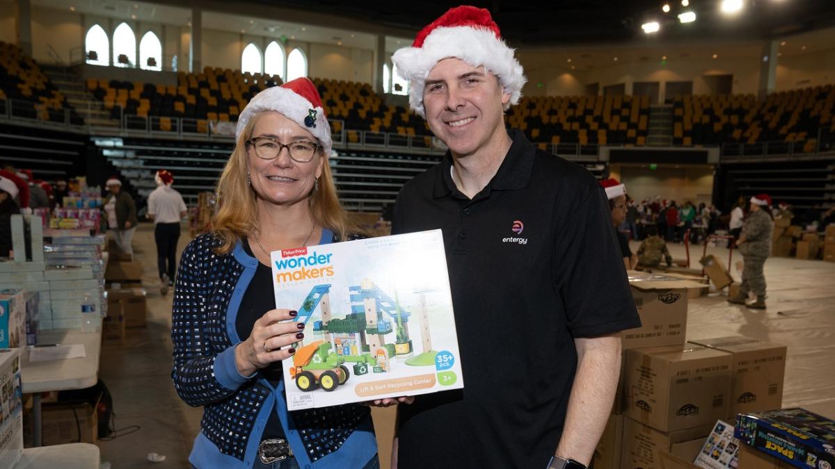 Two volunteers in santa hats posed together with a toy.