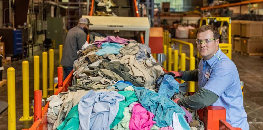 A person next to a line of waste textiles.