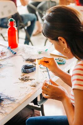 An artisan crafting a bracelet at a table